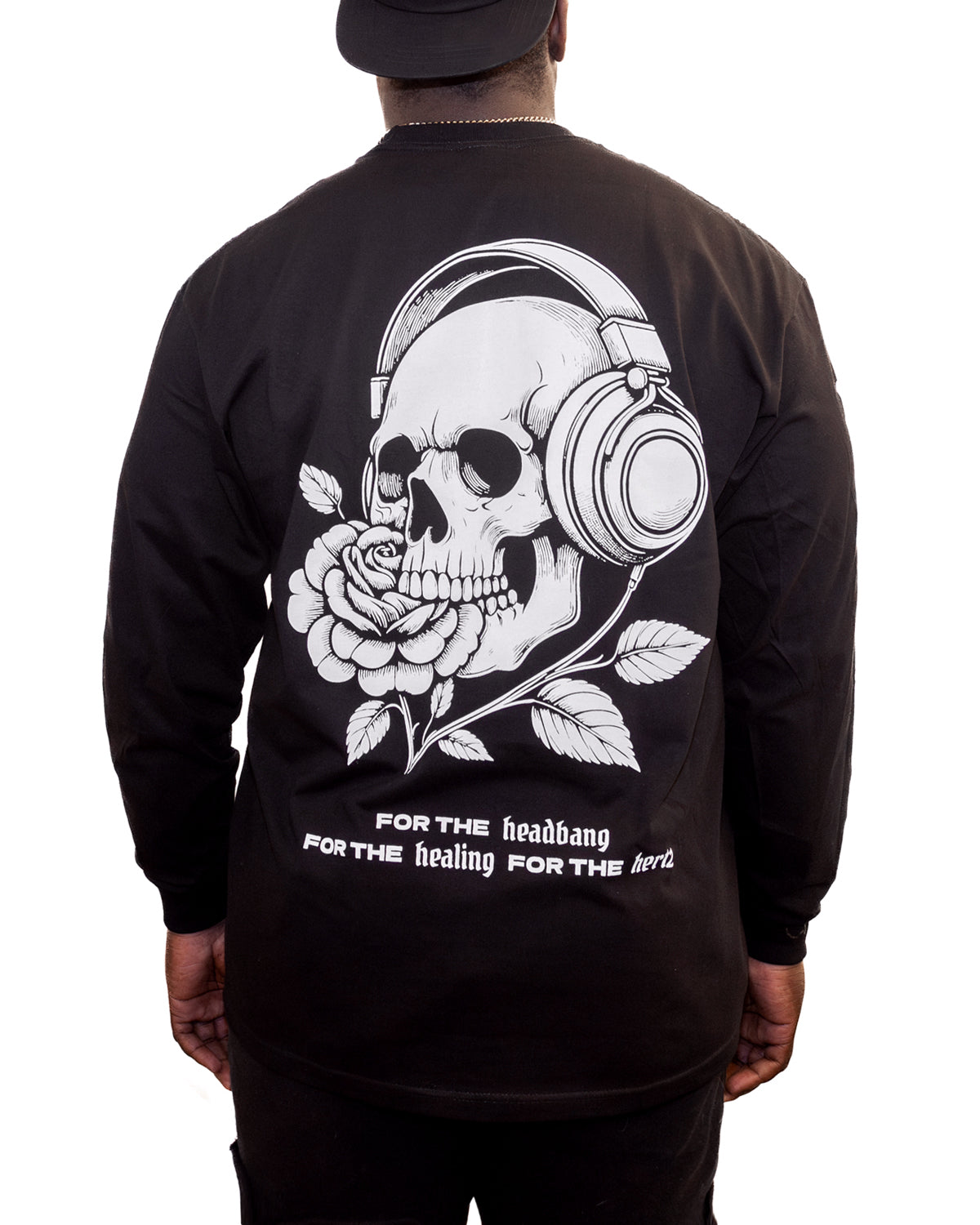 Person wearing long sleeve black t-shirt with a graphic of a skull wearing headphones that turn into a rose on the back.