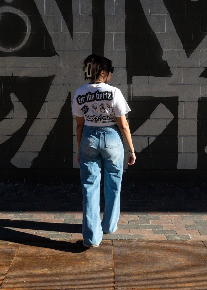 Woman wearing stickers boxy crop t-shirt and jeans in front of a black and white abstract wall.