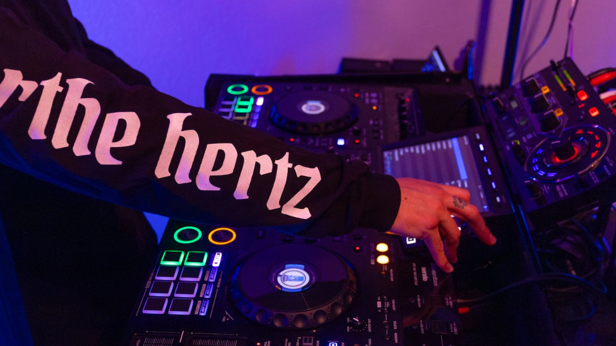 Man playing dj decks wearing skull long sleeve with for the hertz on the sleeve.