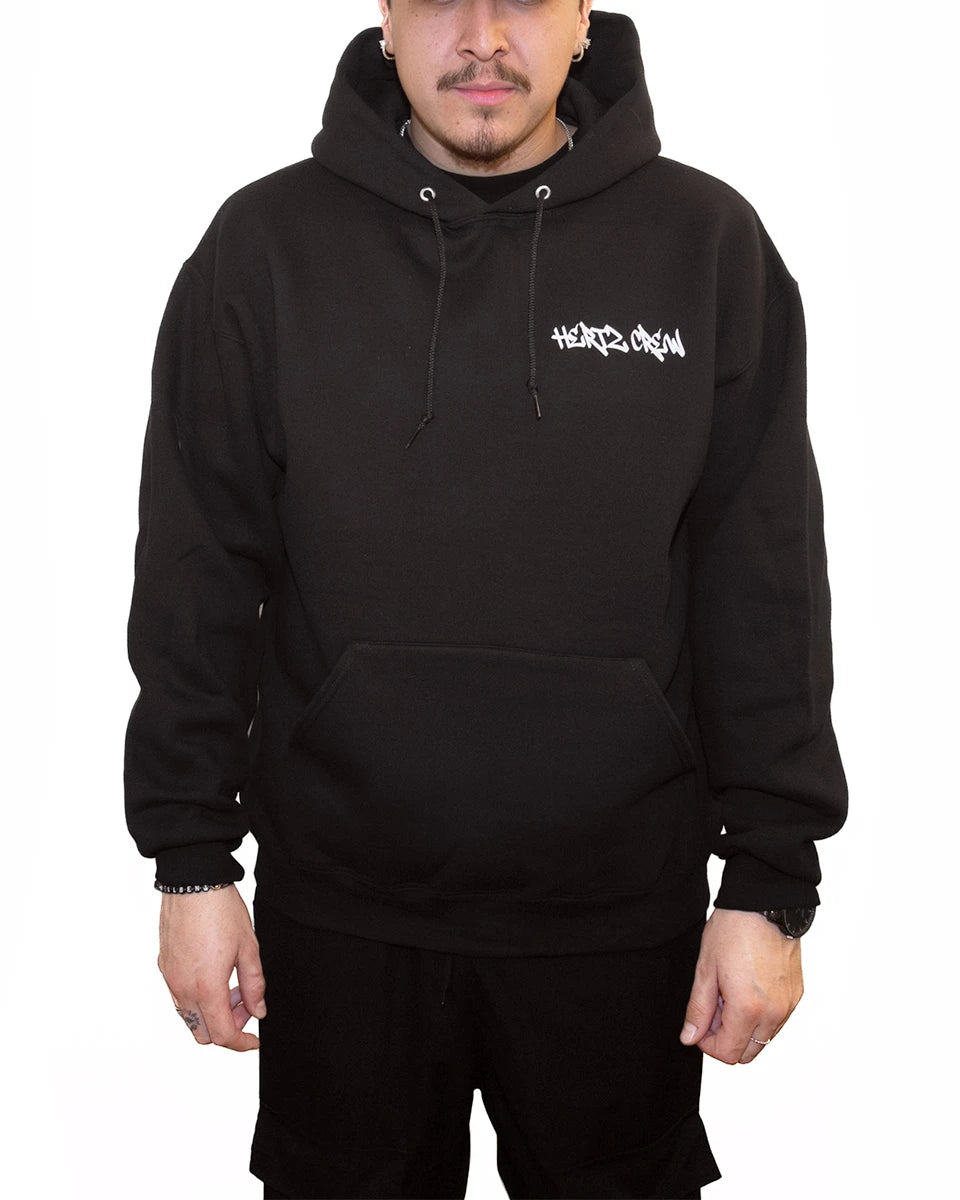 Person wearing a black hooded sweatshirt with hertz crew in graffiti font on the front pocket area.