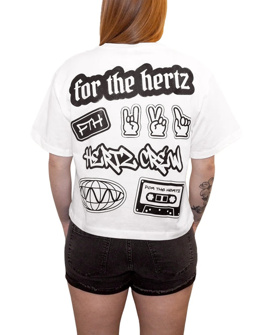 Red headed woman wearing white boxy crop t-shirt with text and graphic stickers on the back and black shorts