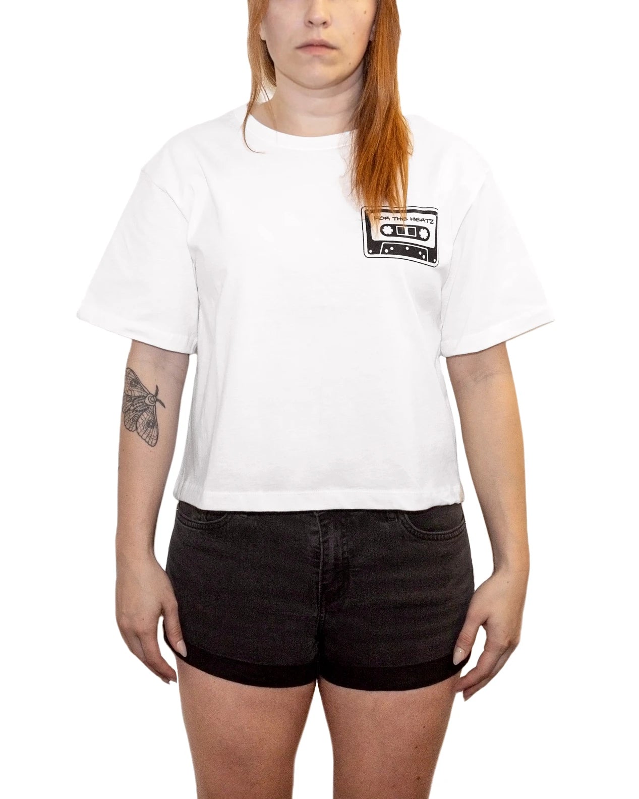 Woman wearing a boxy crop white t-shirt with a cassette tape graphic and black shorts